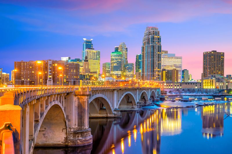 Downtown Minneapolis and an arched bridge reflected in the Mississippi at dusk, the northern end of Upper Mississippi cruises